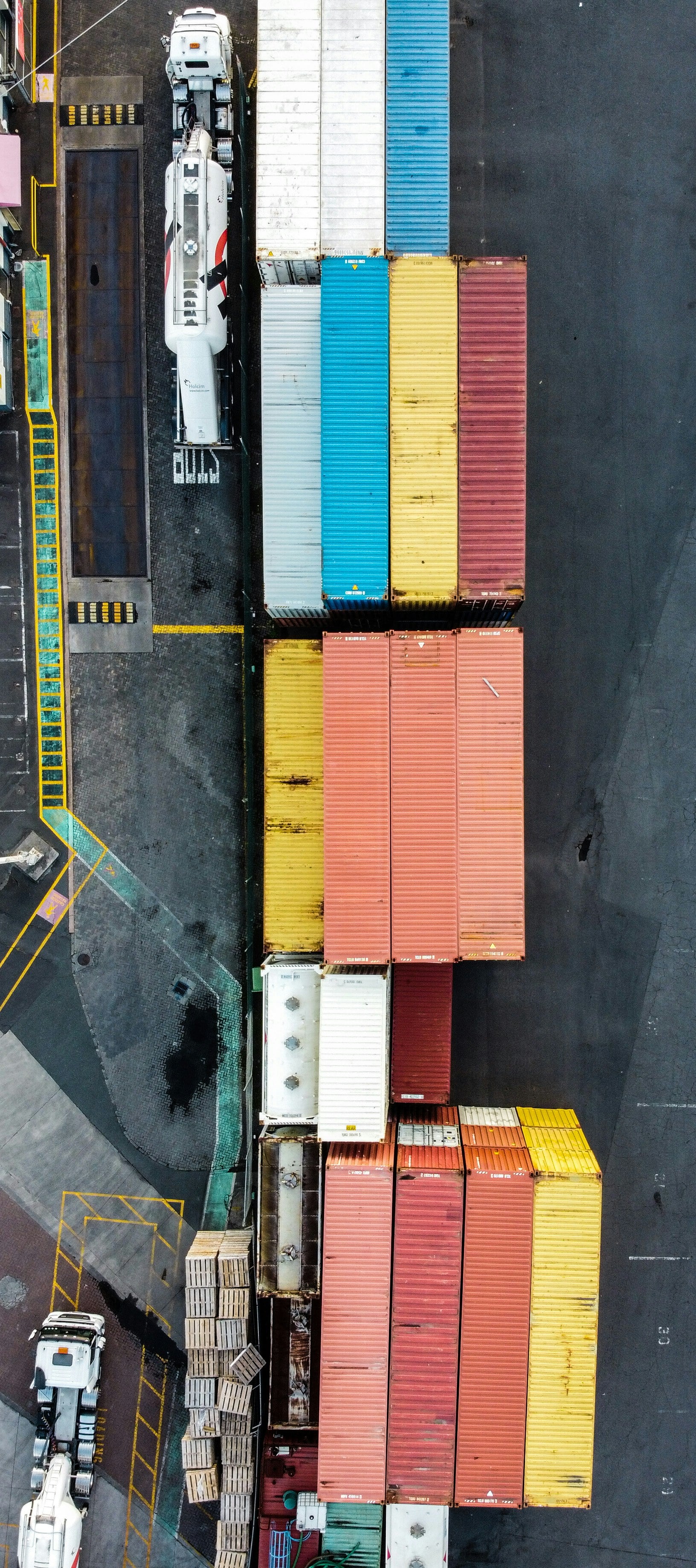 Aerial view of a container yard — rows of containers with trucks threading between them.